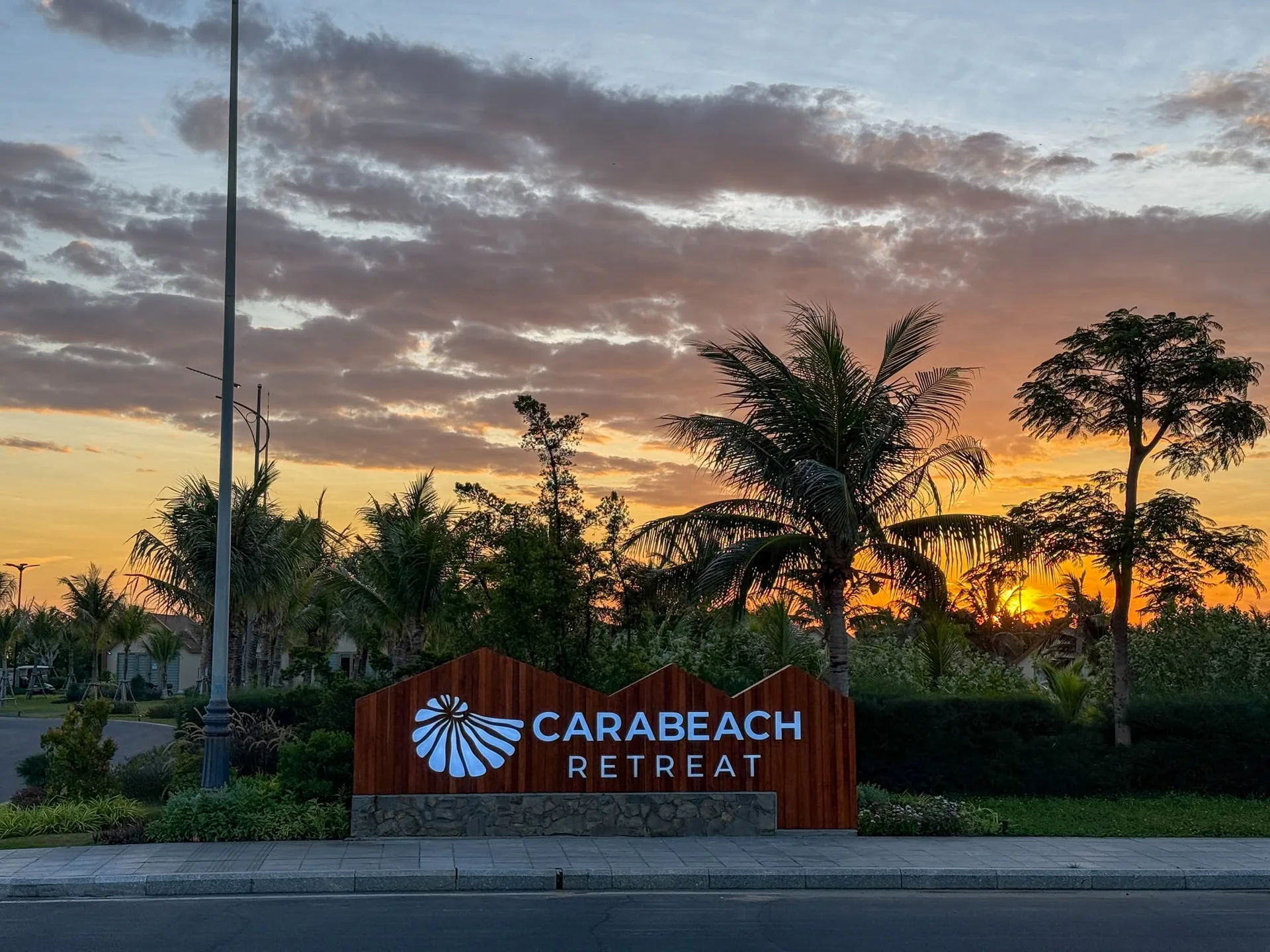 Bảng hiệu cổng gỗ khu nghỉ dưỡng biển CaraBeach Retreat dưới &aacute;nh ho&agrave;ng h&ocirc;n B&atilde;i D&agrave;i