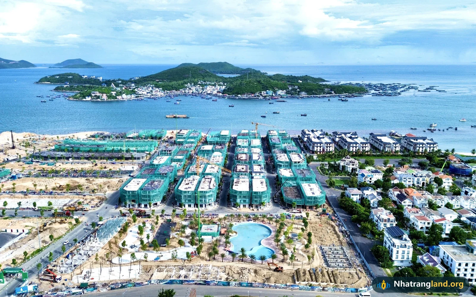 Ảnh flycam thực tế th&aacute;ng 10/2026 tiến độ c&ocirc;ng trường Vinhomes Pearl Bay Nha Trang với hồ bơi trung t&acirc;m đ&atilde; t&iacute;ch nước v&agrave; h&agrave;ng loạt d&atilde;y cất n&oacute;c 4 tầng