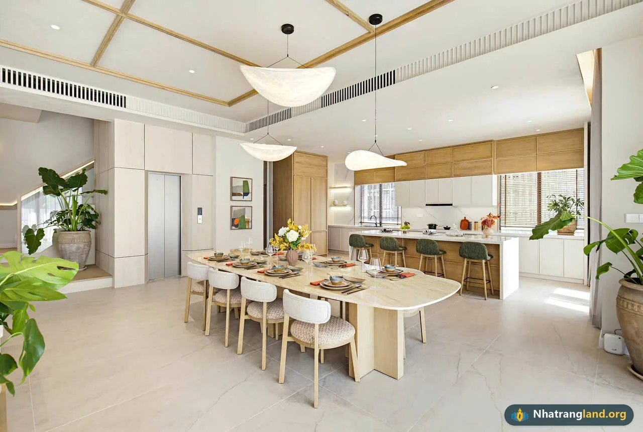 Ảnh chụp thực tế khu vực bàn ăn nguyên khối, đảo bếp mở và thang máy kính bên trong Căn mẫu Biệt thự Song lập The Elite