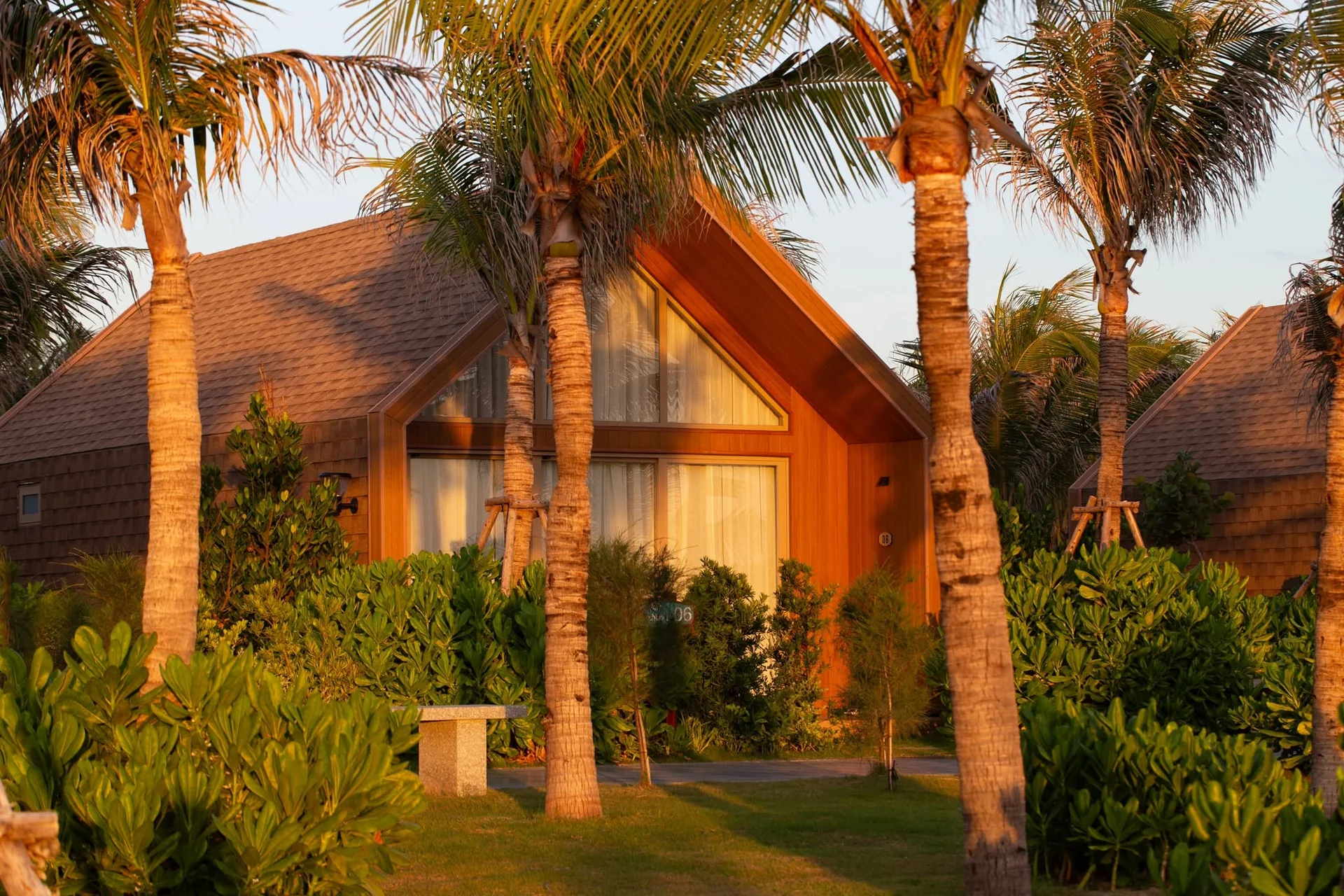 Căn Bungalow gỗ m&aacute;i chữ A l&ecirc;n đ&egrave;n v&agrave;ng ấm &aacute;p v&agrave;o buổi tối dưới rặng dừa CaraBeach Retreat