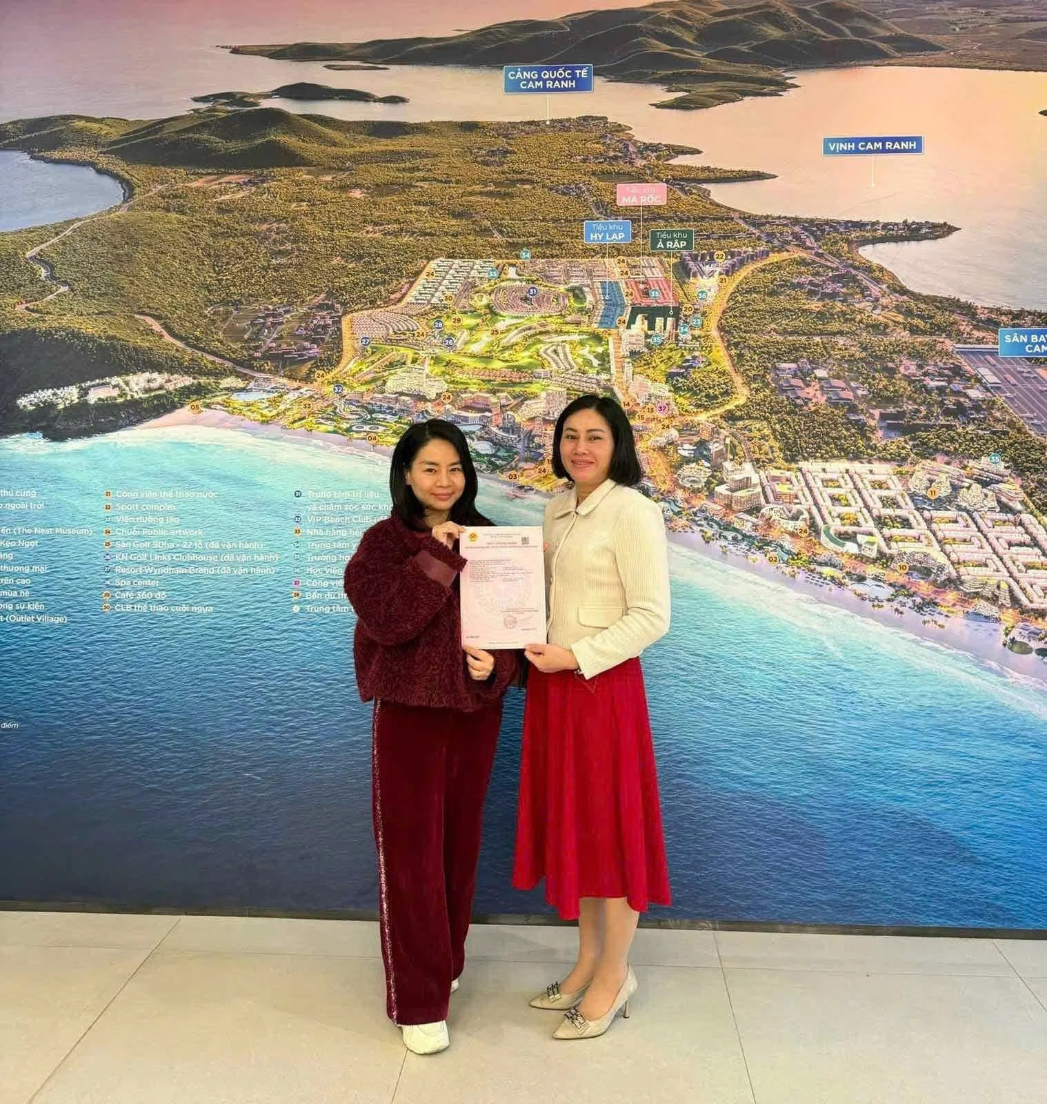 Chủ sở hữu cầm trên tay Sổ hồng lâu dài CaraWorld Cam Ranh chụp lưu niệm trước phối cảnh tổng thể Vịnh Cam Ranh