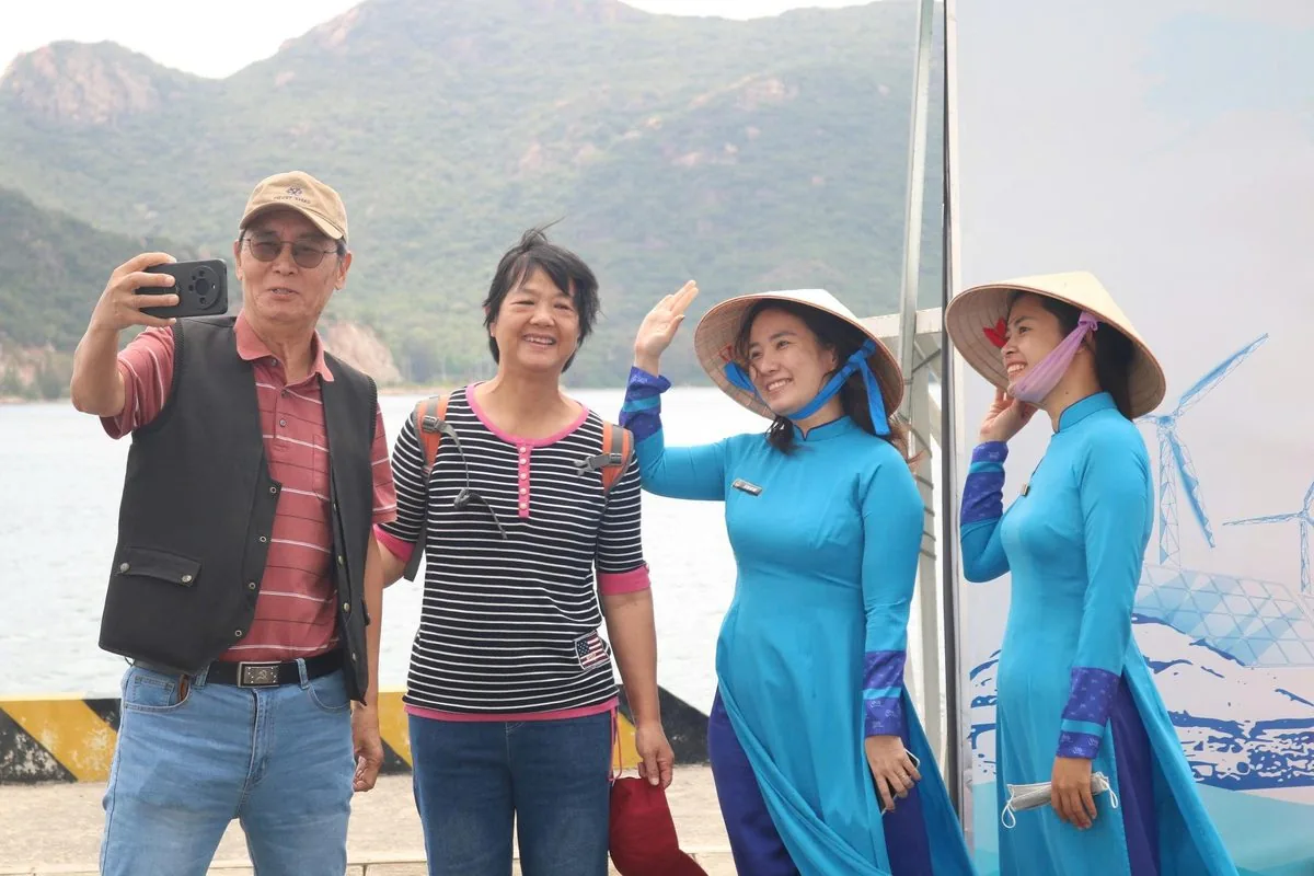 Du khách quốc tế chụp ảnh selfie với nhân viên đón tiếp mặc áo dài truyền thống tại cảng Cam Ranh