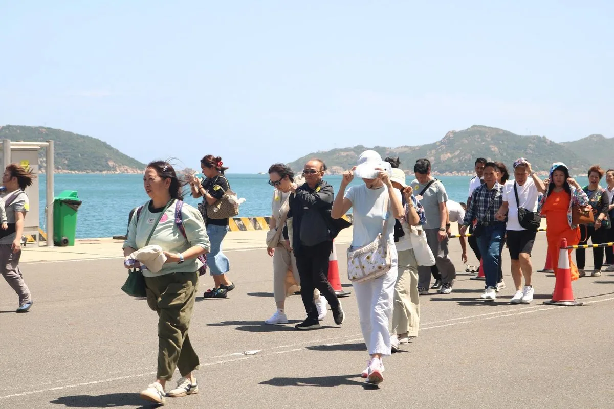 Du khách quốc tế từ tàu Star Voyager đi bộ tại cảng Cam Ranh với biển xanh ngắt phía sau